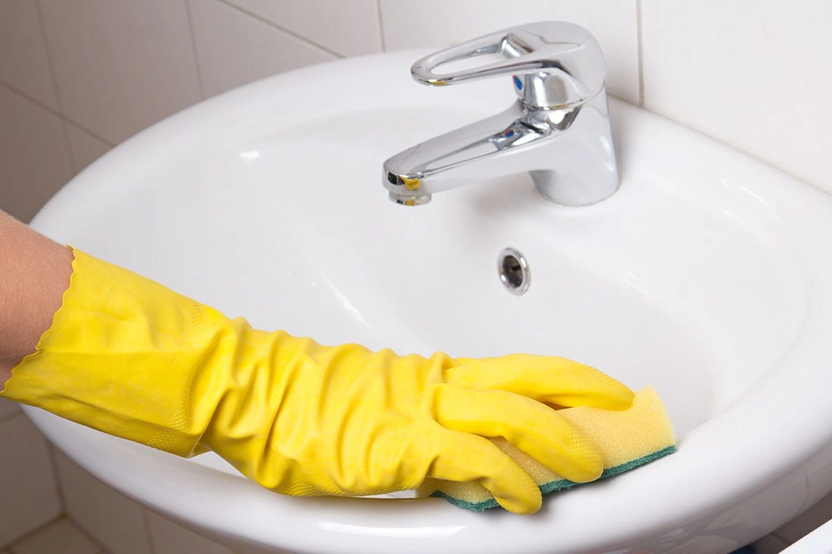 Een man maakt de wastafel schoon