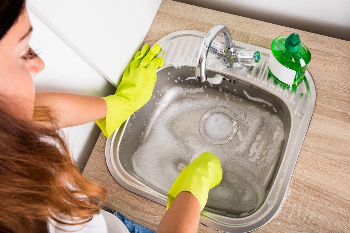iemand maakt de wastafel schoon