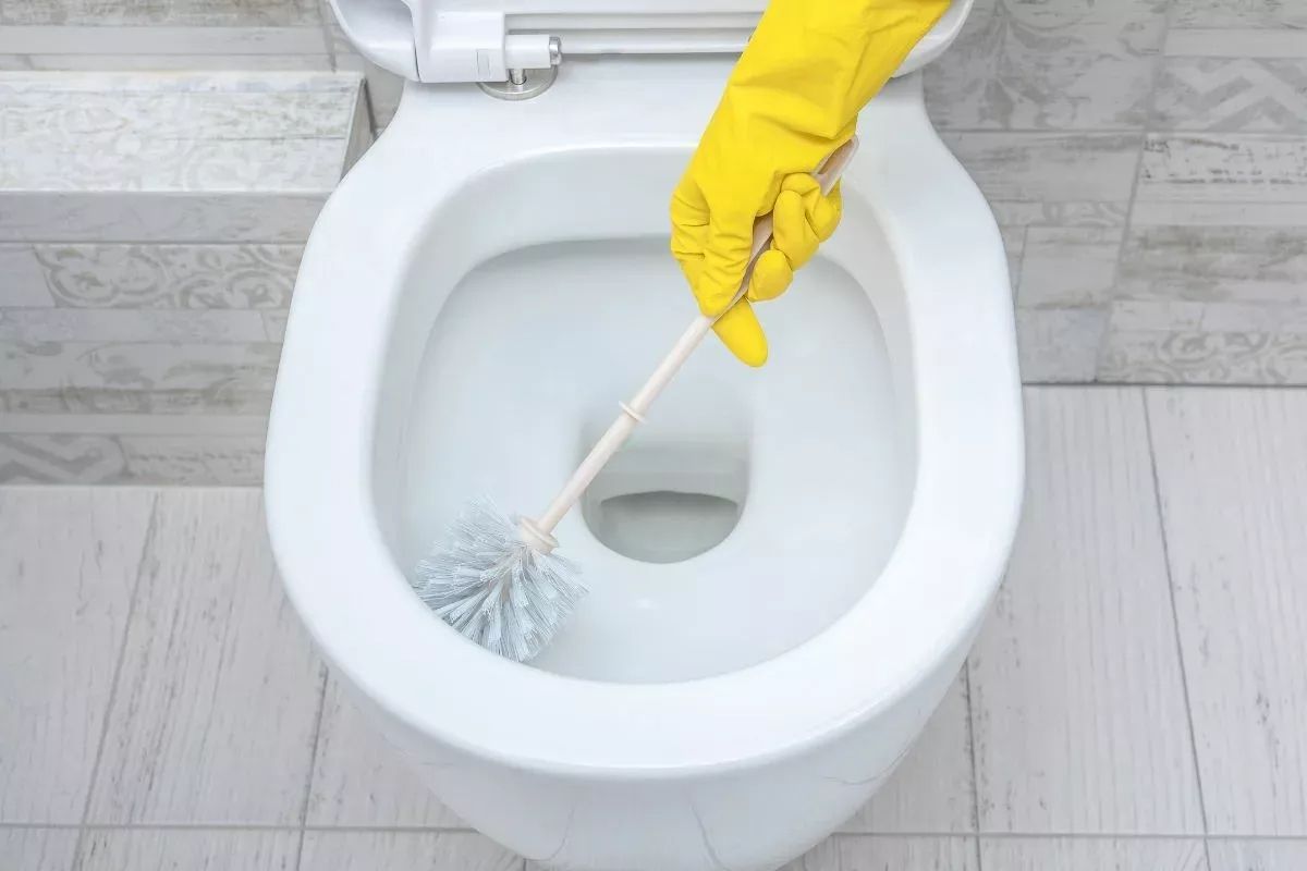 iemand schrobt de kalkaanslag in het toilet weg