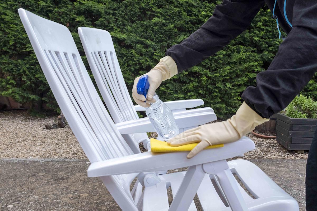 Een man maakt tuinmeubels schoon