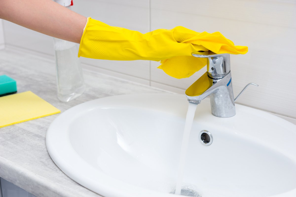 Een man maakt de kraan schoon